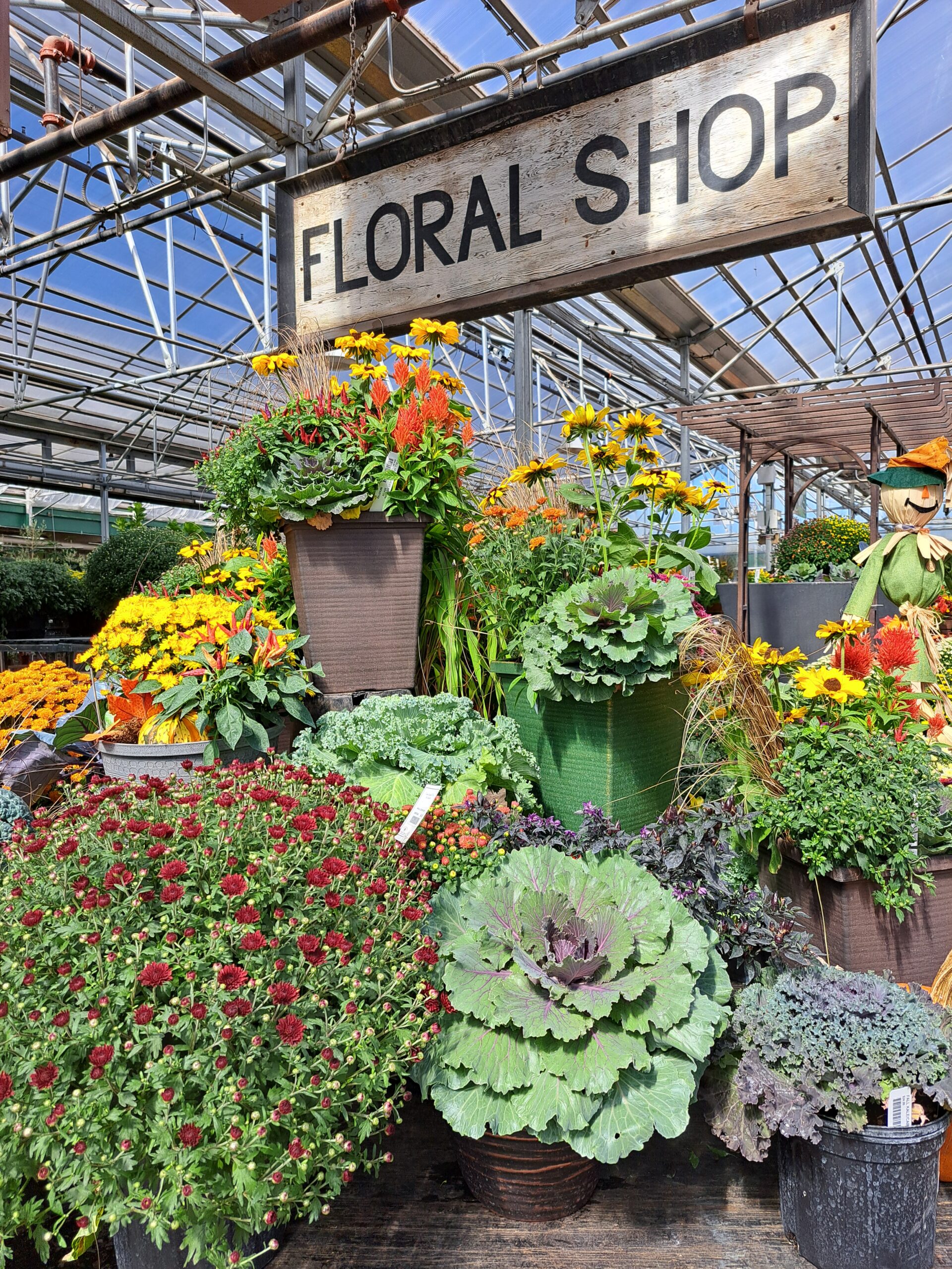 multiple potted plants and flowers sitting below a large floral shop sign - custom retaining walls